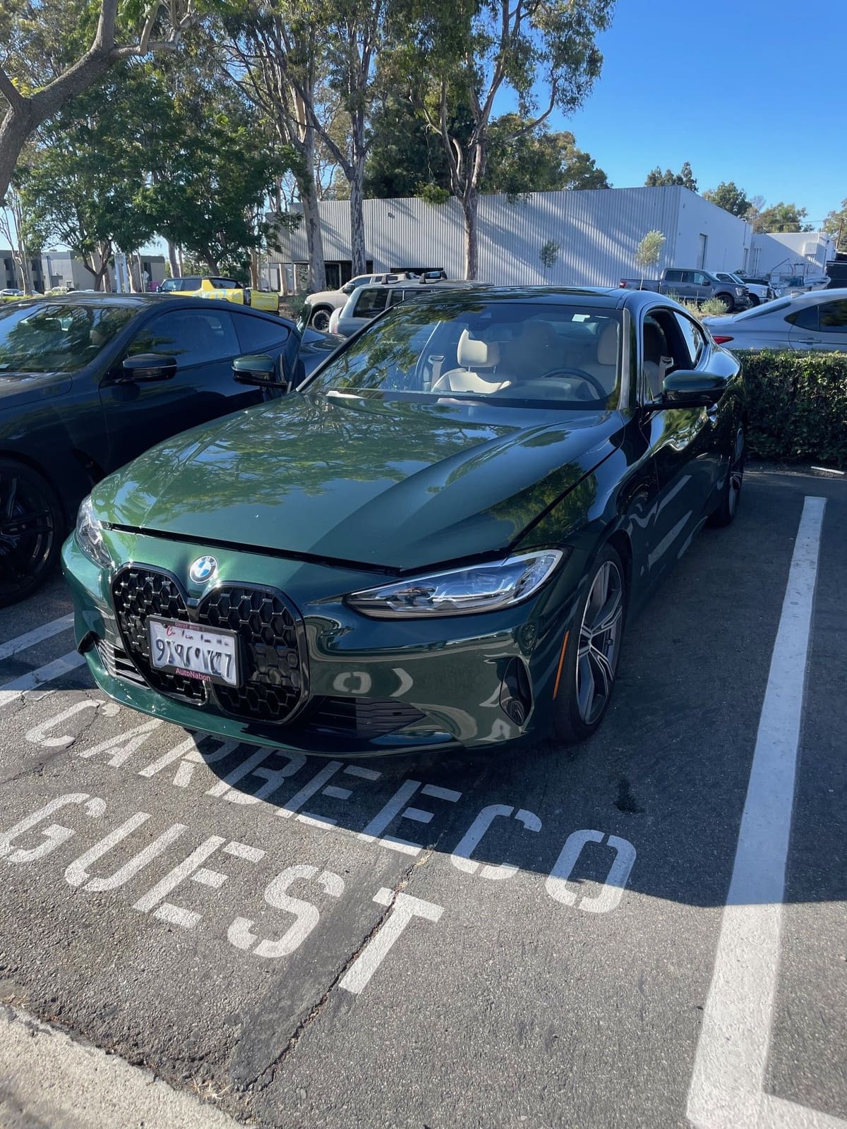 Dark green BMW 4 Series coupe in a dealership parking space